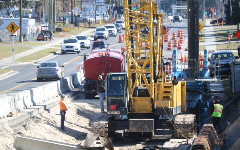 Construction workers use an excavator and other heavy machinery Tuesday afternoon while working on U.S. Highway 90 during a sheet piling operation to stabilize the roadway. (TONY BRITT/Lake City Reporter)