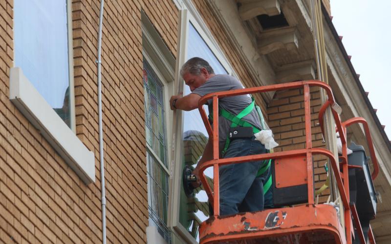 North Florida Glass employees place a new double-paned window on the outside of one of the First Baptist Church of Lake City’s stained-glass windows. (JAMIE WACHTER/Lake City Reporter)