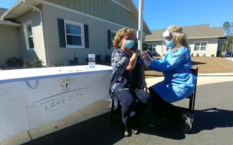 Brenda Lacy, left, receives a vaccination Tuesday from Kristen Tuten, a nurse consultant, at the Rehabilitation Center of Lake City. More than 75 patients and staff of the facility received the second dose of the vaccination Tuesday including Lacy, the Rehab Center’s administrator. (TONY BRITT/Lake City Reporter)