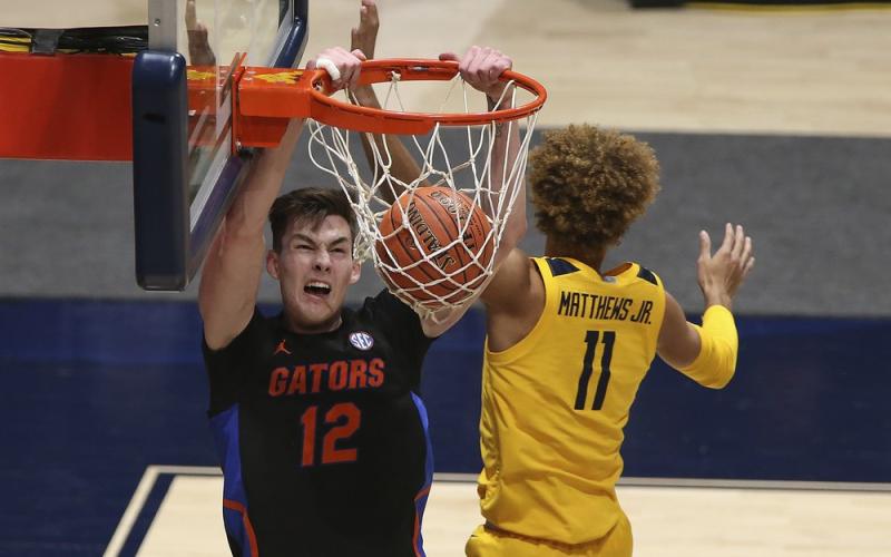 Florida forward Colin Castleton (12) dunks on West Virginia forward Emmitt Matthews Jr. (11) on Saturday in Morgantown, W.Va. (KATHLEEN BATTEN/Associated Press)