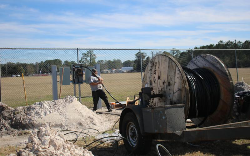 Jay Lambert pulls wire from a large spool while working on upgrades at the Florida Gateway Fairgrounds Rodeo Arena. The facility is adding more RV campsites for events. (TONY BRITT/Lake City Reporter)