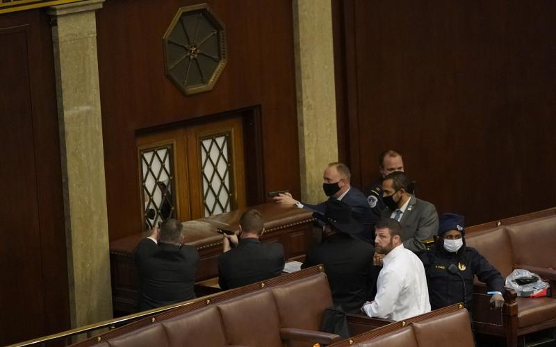 U.S. Capitol police officers point their guns at a door that was vandalized in the House Chamber during a joint session of Congress on Wednesday in Washington, D.C. (DREW ANGERER/Getty Images/TNS)