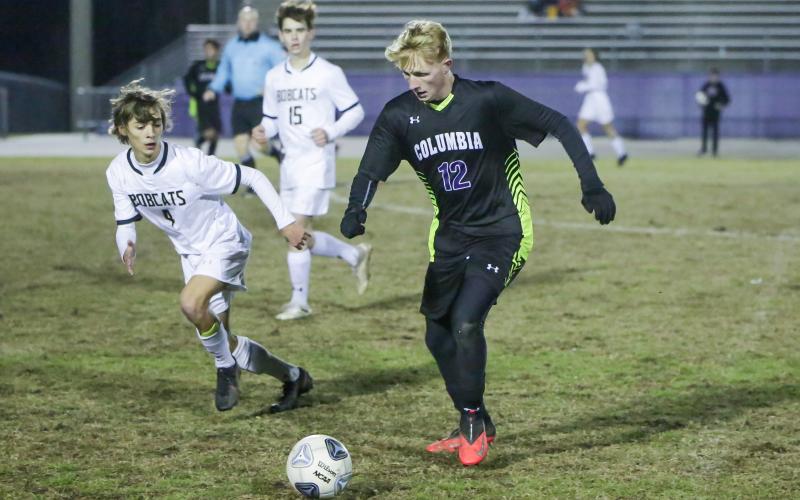 Columbia’s Zack Strickland dribbles up the field while Buchholz’s Riley Smith gives chase during Wednesday’s District 2-6A semifinals. (BRENT KUYKENDALL/Lake City Reporter)