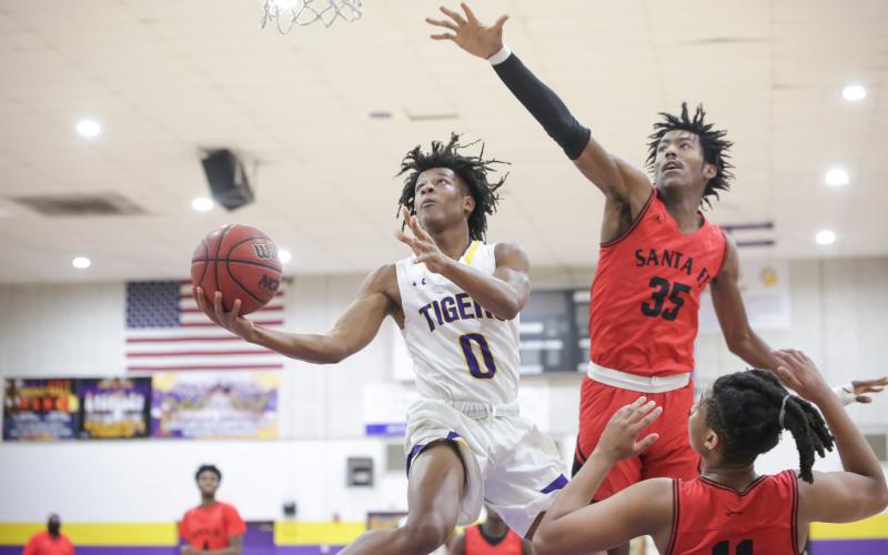 Columbia guard Dante Brown soars past Santa Fe center Jonathan Lee to score a layup on Thursday night. (BRENT KUYKENDALL/Lake City Reporter)