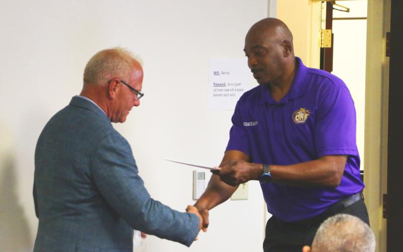 Gary Wilson (from left) receives a thank-you note and handshake from Columbia track &amp; field coach Lawrence Davis during Thursday’s meeting. (MORGAN MCMULLEN/Lake City Reporter)