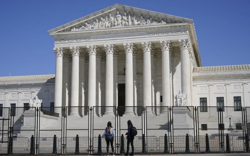 People view the Supreme Court building from behind security fencing on Capitol Hill on March 21 in Washington after portions of an outer perimeter of fencing were removed overnight to allow public access. A Supreme Court case being argued this week amid March Madness could erode the difference between elite college athletes and professional sports stars. (AP FILE PHOTO)
