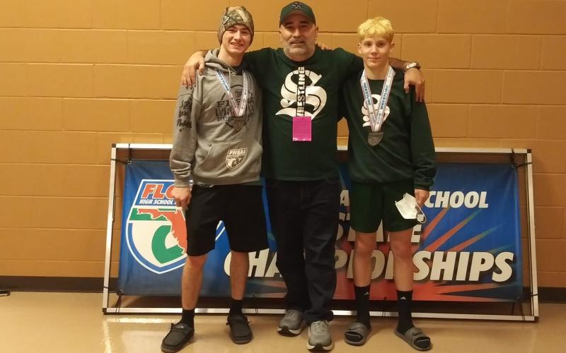 Suwannee wrestlers Timothy Jolicoeur (left) and Austin McKinney (right) stand with coach John Wainwright after reaching the medal stand at the Class 1A state meet on Saturday. (COURTESY)