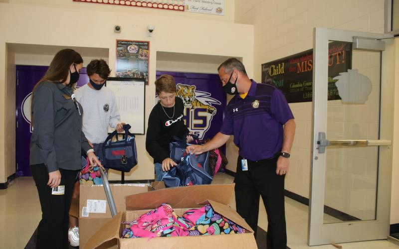 Stacy Albritton, DCF supervisor of Child Investigations (from left), stands with A.J. Kihei, Columbia High School student body president, Elijah Dockery, chairman of the Hope Bags Drive and Trey Hosford, Columbia High School principal, as they look at Hope Bags that will be donated to local children in foster care. (TONY BRITT/Lake City Reporter)