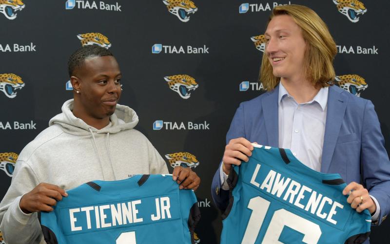 Former Clemson teammates and now Jaguars teammates running back Travis Etienne, left, and quarterback Trevor Lawrence pose with their new teal jerseys prior to an introductory press conference on April 30 at TIAA Bank Field in Jacksonville. (BOB SELF/TNS)