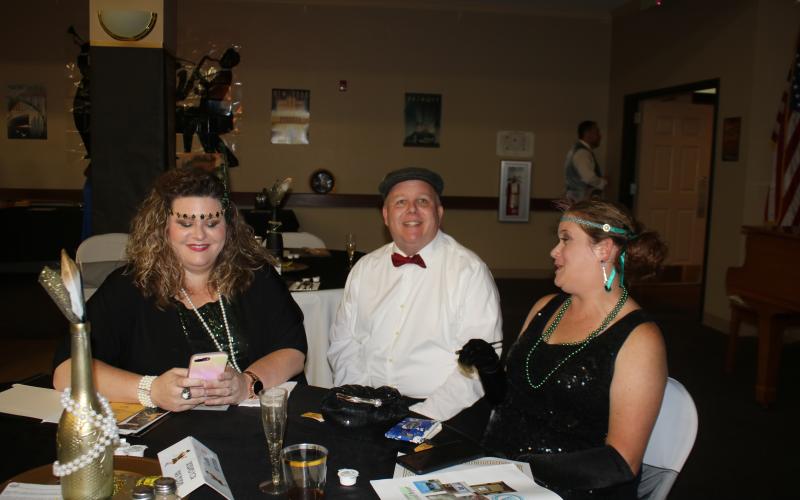 Renee Williams (from left), Columbia County Senior Services Executive Director David Huckabee and Courtney Barga share a conversation during the “Roaring 20s”, a fundraising kickoff event for Columbia County Senior Services Friday evening at the Lifestyle Enrichment Center in Lake City. (TONY BRITT/Lake City Reporter)
