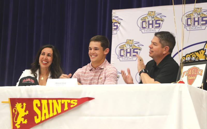 Columbia shortstop Mason Gray (middle) smiles after signing his letter of intent with Flagler alongside his mother, Heather, and father, Kevin, on Tuesday. (MORGAN MCMULLEN/Lake City Reporter)