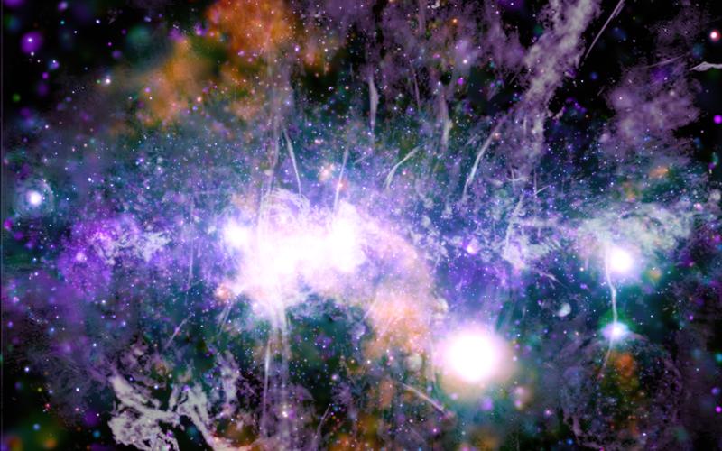 This false-color X-ray and radio frequency image made available by NASA on Friday, May 28, 2021 shows threads of superheated gas and magnetic fields at the center of the Milky Way galaxy. X-rays detected by the NASA’s Chandra X-ray Observatory are in orange, green, blue and purple, and radio data from the MeerKAT radio telescope in South Africa are shown in lilac and gray. The plane of the galaxy is horizontal, in the center of this vertical image. (NASA/CXC/UMass/Q.D. Wang)