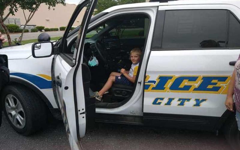 Five-year-old Wyatt Griffis sits in the patrol vehicle of Lake City police officer Michael Craig following an interaction between the two near a Dollar Tree store. (COURTESY)