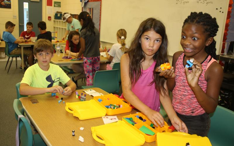 Columbia City Elementary students Jasom Chase (from left), Johanna Angelo and Cache Sheppard play with a set of Legos Wednesday morning. (TONY BRITT/Lake City Reporter)