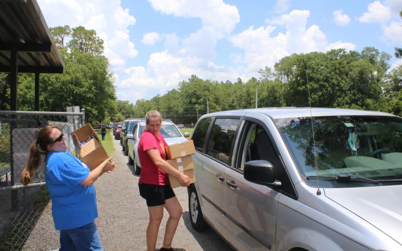 Alicia Blackford (left) and Laurie Renegar carry meals to a minivan Thursday afternoon at Five Points Elementary School. (TONY BRITT/Lake City Reporter)