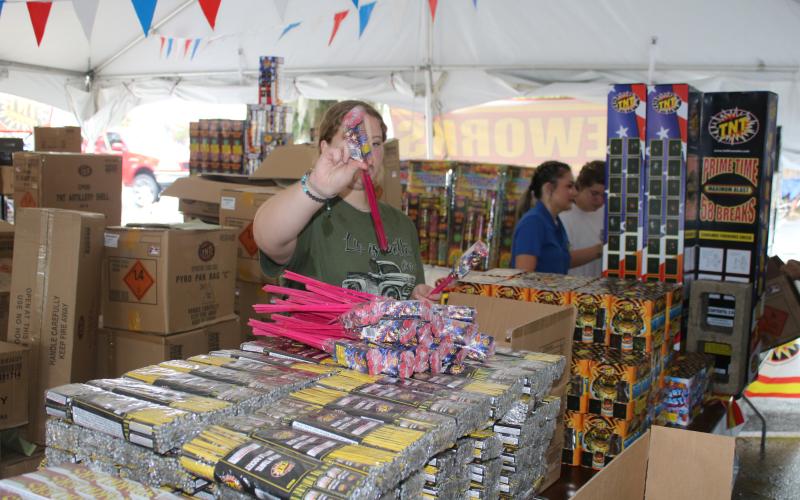 Kaleigh Clements, a Lake City Middle School student, arranges packs of bottle rockets Thursday at the CHS FFA Chapter TNT fireworks tent. Proceeds raised from the sales will be used to help fund the CHS FFA program. (TONY BRITT/Lake City Reporter)