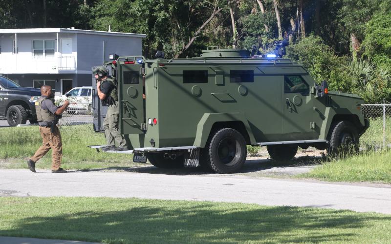 Law enforcement officers gather outside a building at the intersection of SW Main Boulevard and SW Ivan St. Monday afternoon after a man barricaded himself inside. (MORGAN MCMULLEN/Lake City Reporter)