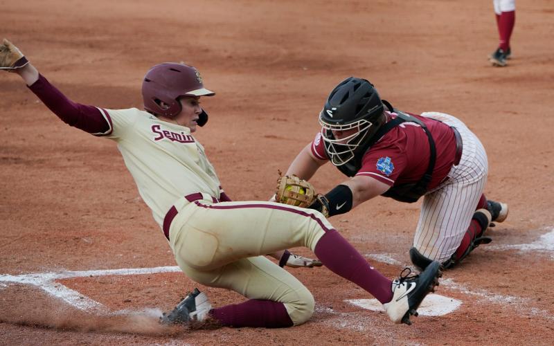 Florida State’s Dani Morgan, left, slides home safely as Alabama catcher Bailey Hemphill reaches in for the tag in the third inning of Monday’s Women’s College World Series semifinal game in Oklahoma City. (SUE OGROCKI/Associated Press)