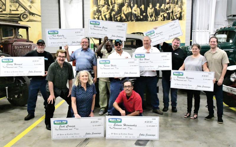 Nine Waste Pro employees were surprised recently with a $10,000 bonus for 20 years of service to the company, which was founded 20 years ago in Central Florida. Employees honored included, in front, Judi Craigo (from left) and Edwin Hernandez; in back, Larry Harned, Executive Board Chairman and founder John Jennings, Ted Oglesby, William Green, Kevin Wells, Neil Wood, Frank Kramer, Vanessa Kramer and Sean Jennings. (COURTESY)