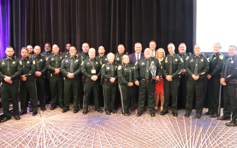 Sergeant Tim Ball (holding trophy) is joined by the 19 officers that make up the CCSO School Resource Unit Monday at the annual Florida Association of School Resource Officers conference. (COURTESY)