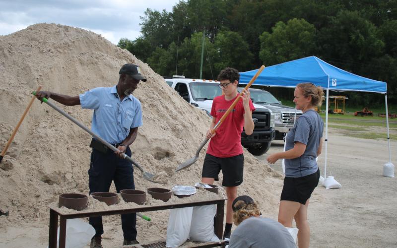 Neville Taylor (from left), a Columbia County Public Works employee, helps Micah Taber and Lisa Taber as they fill sandbags at the Columbia County Public Works Construction Yard Tuesday afternoon. (TONY BRITT/Lake City Reporter)