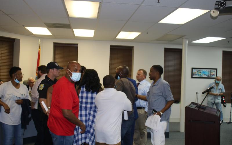 Conrad Wallace (foreground) and others attempt to restrain Sylvester Warren as he engages in a verbal confrontation with council member Eugene Jefferson. (TONY BRITT/Lake City Reporter)