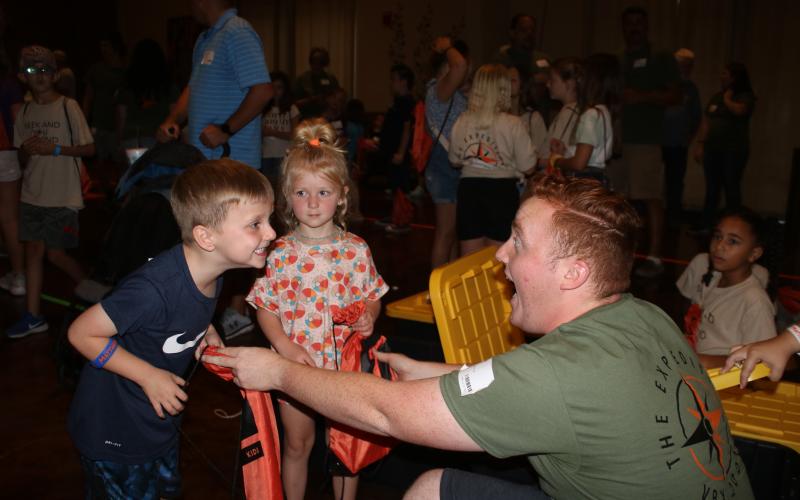 Easton Helsel (left), 5, makes a face with Jacob English (far right) during the Christ Central Vacation Bible School session Wednesday night as Emery Helsel, 4, looks on while English gives them drawstring book bags. (TONY BRITT/Lake City Reporter)