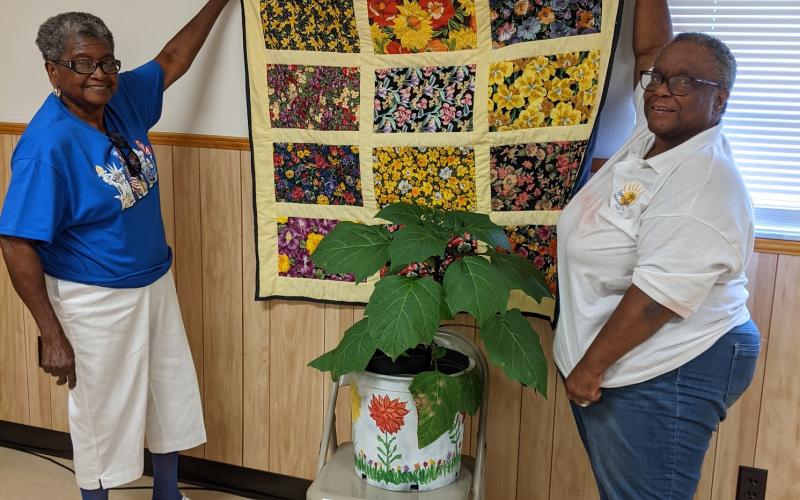 Oleatha Harris (from left) presented Gloria Bradley a Purple Angel Trumpet Plant and lap roll quilt for her service to the community and years of friendship. (COURTESY)