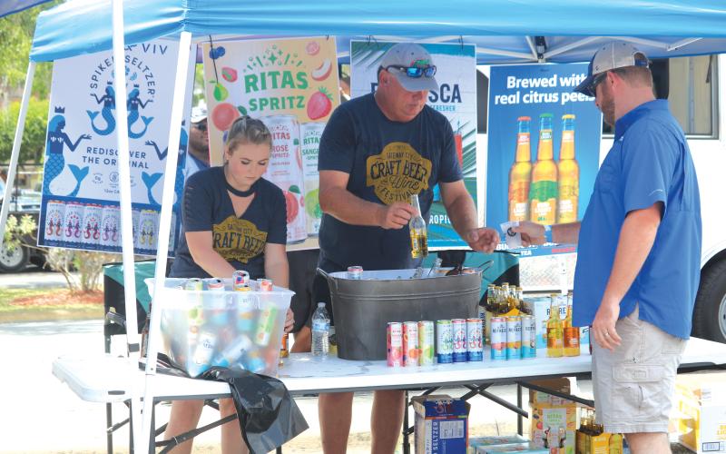 A pair of craft beer vendors deliver service to an attendee of the 2019 Gateway City Craft Beer &amp; Wine Festival. (FILE)