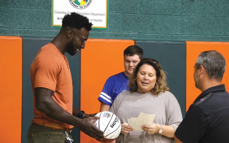 Former Gators basketball standout Patric Young (left) looks over a basketball signed by former members of the University of Florida team as Eli Stewart and Laura Lashley reminisce about Eli’s visit to a UF sports camp. (MORGAN MCMULLEN/Lake City Reporter)