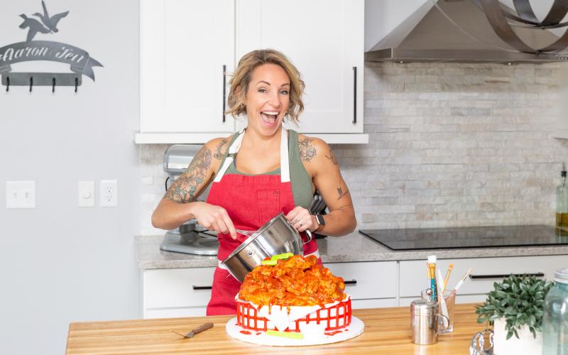 Amy Strickland puts the finishing touches on a cake, decorated as a basket of hot wings. (BRENT KUYKENDALL/Lake City Reporter)