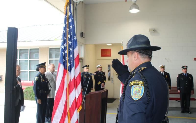 A Lake City police officer salutes the American flag Thursday at the start of the 9/11 memorial ceremony. (TONY BRITT/Lake City Reporter)