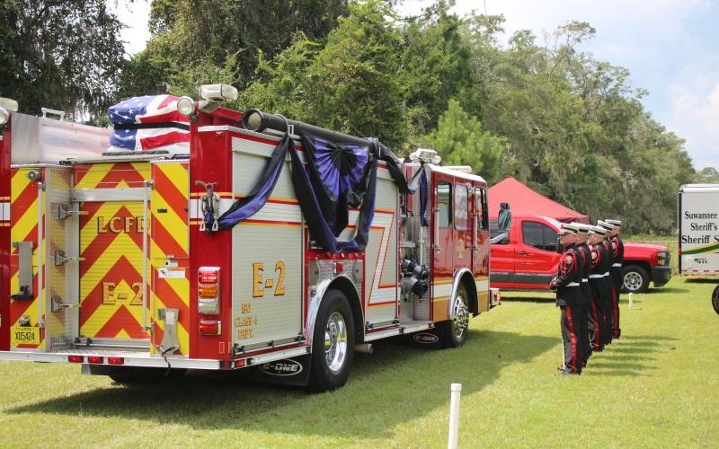 Members of the Suwannee County Fire Rescue honor guard stand at attention at the Corinth Methodist Church cemetery alongside the Lake City fire engine carrying Fire Chief Randy Burnham on Friday. (TONY BRITT/Lake City Reporter)