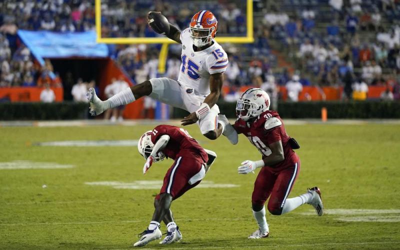 Florida quarterback Anthony Richardson (15) hurdles Florida Atlantic defensive back Justin McKithen (11) and safety Armani-Eli Adams (30) on Sept. 4 in Gainesville. (JOHN RAOUX/Associated Press))