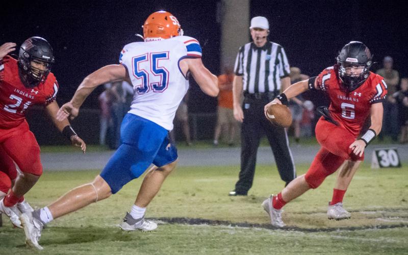 Fort White quarterback Clayton Philpot evades pressure from Branford linebacker Devin Mosley on Friday night. (CHRISTINA FEAGIN/Special to the Reporter)