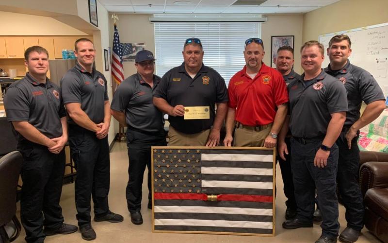Suwannee County Fire Chief Eddie Hand (center) and Division Chief Matt Garbett present the Lake City Fire Department with a fire hose flag in memory of Chief Randy Burnham. (COURTESY)