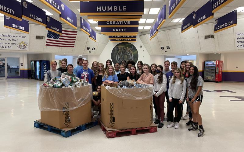 Students at Columbia High School gather around a pair of boxes containing donated canned and dry foods to be given to charity. (COURTESY)