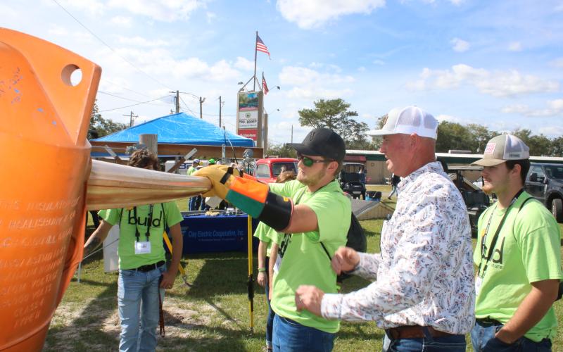 Ethan Humphries (center), a Branford High School student, uses gloves while getting tips from Eric Crawford, a Clay Electric line supervisor, during Wednesday’s Build My Future event. (TONY BRITT/Lake City Reporter)