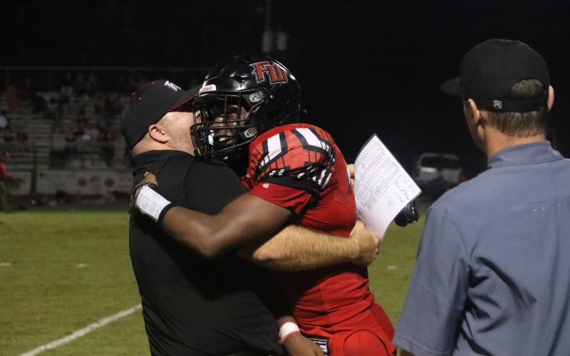 Fort White fullback Kamarion Griffin hugs a coach Friday night after an 85-yard touchdown run. (MORGAM MCMULLEN/Lake City Reporter)