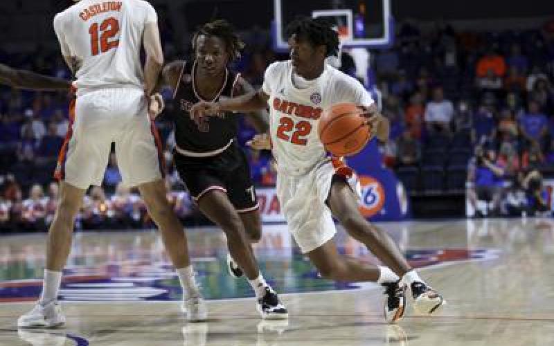 Florida guard Tyree Appleby (22) dribbles around Troy guard Christyon Eugene (5) during Sunday’s game in Gainesville. (MATT STAMEY/Associated Press)
