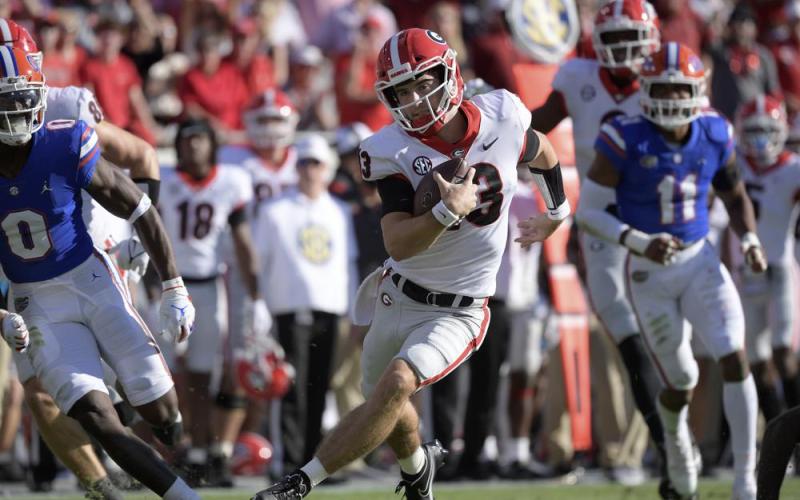Georgia quarterback Stetson Bennett (13) scrambles for yardage in front of Florida safety Trey Dean III (0) and linebacker Mohamoud Diabate (11) on Oct. 30 in Jacksonville. (PHELAN M. EBENHACK/Associated Press))