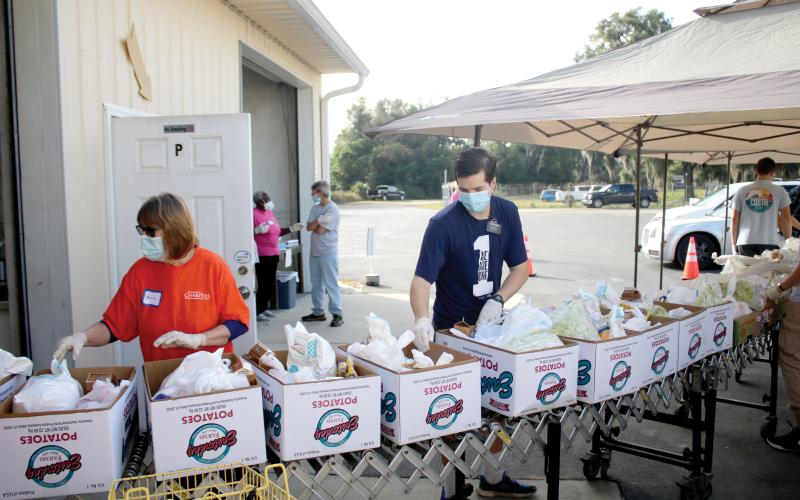 Volunteers put food into Thanksgiving baskets Thursday morning at Catholic Charities. More than 90 volunteers helped distribute 565 Thanksgiving baskets to local families. (TONY BRITT/Lake City Reporter)