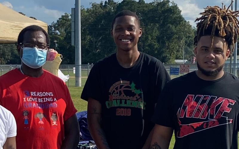 Dr. Tommy Randolph (from left), D’Andre Jefferson and Thomas Williams pose at last year’s clothing drive. (COURTESY)