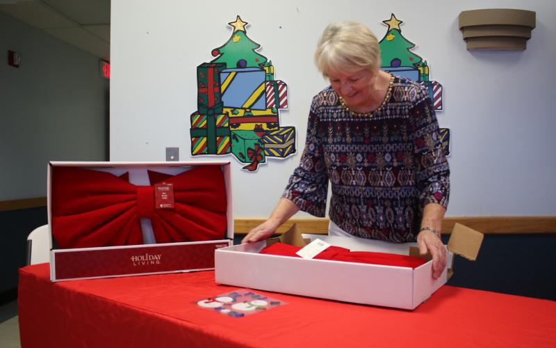 Christmas Dream Machine founder and director Meally Jenkins opens up boxes of giant bows as part of her preparations for this year’s event at 1445 SW Main Boulevard. (TONY BRITT/Lake City Reporter)