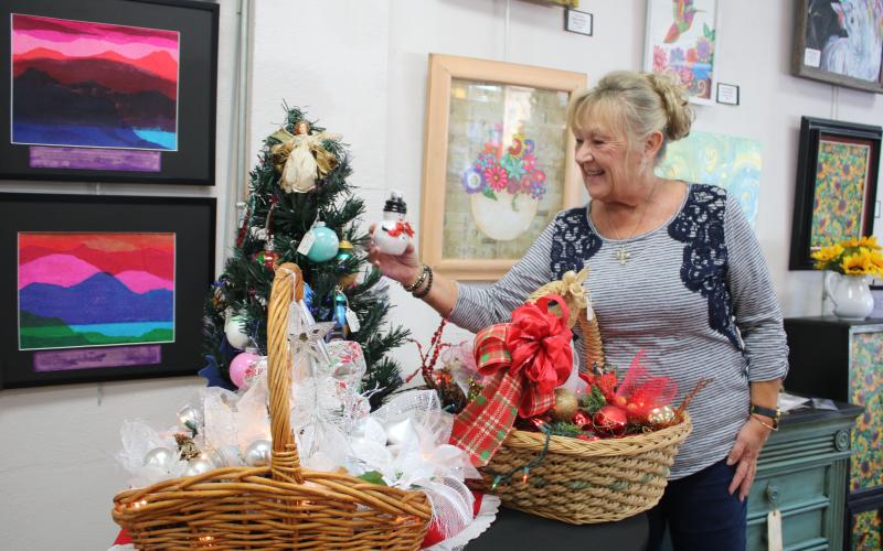 Cindy Sleezer checks out a snowman ornament at the Gateway Art Gallery. (TONY BRITT/Lake City Reporter)