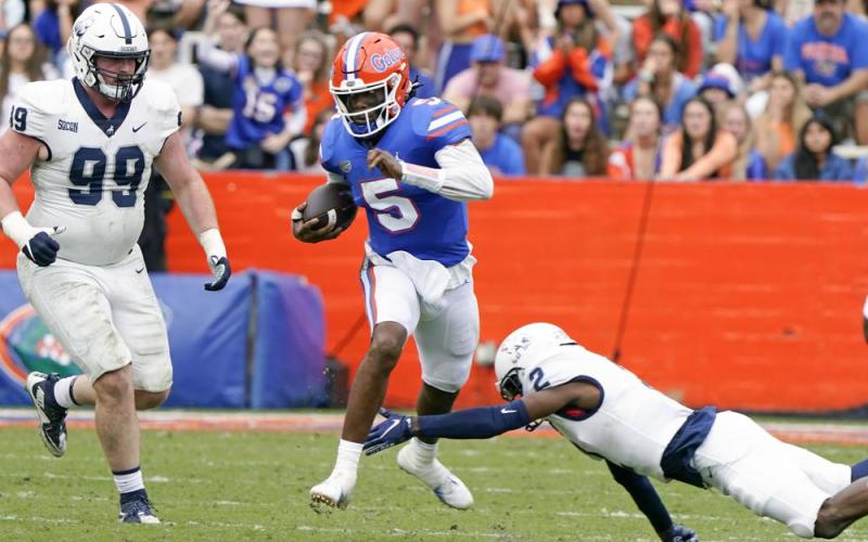 Florida quarterback Emory Jones (5) scrambles for yardage as he gets past Samford defensive tackle Seth Simmer (99) and cornerback Coutrell Plair, right, during Saturday's game in Gainesville. (JOHN RAOUX/Associated Press)
