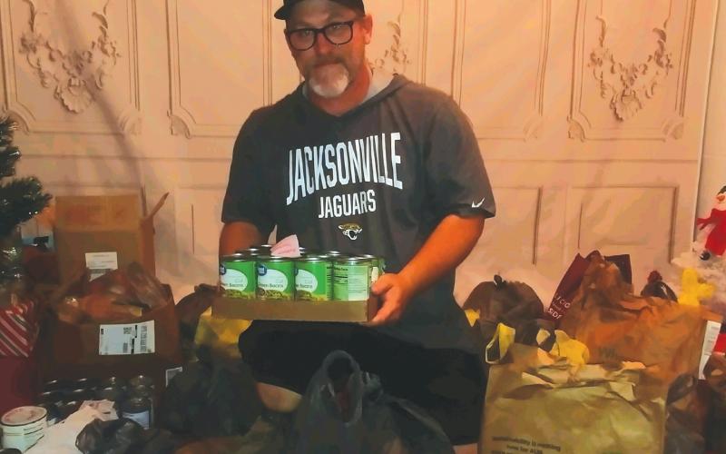 John Cole III, CEO of Saving Our Children, shows off the donated food items that will be given out to local families on Nov. 20. (TONY BRITT/Lake City Reporter)