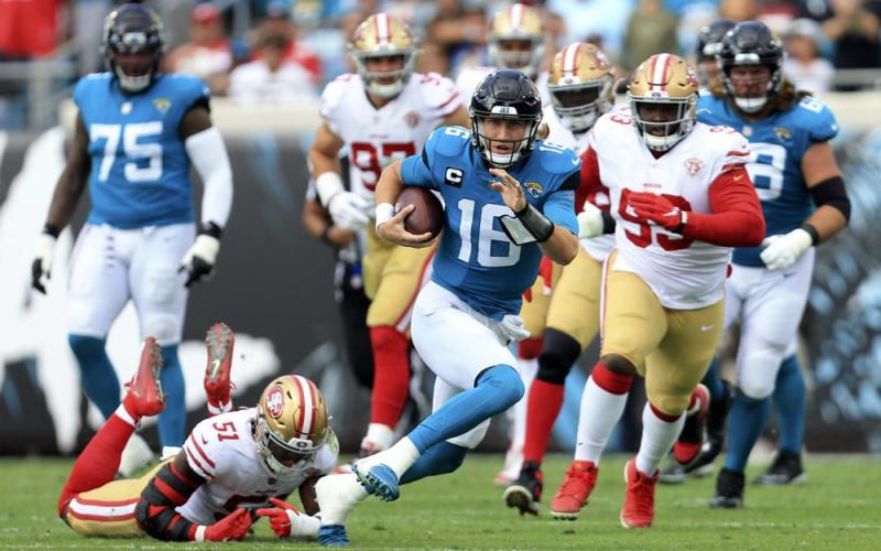 Jacksonville Jaguars quarterback Trevor Lawrence scrambles for yardage as he gets away from San Francisco 49ers linebacker Azeez Al-Shaair (51) and defensive tackle D.J. Jones, right, during Sunday's game in Jacksonville. (MATT STAMEY/Associated Press)