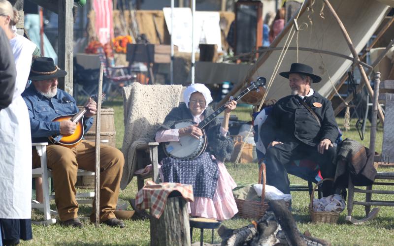 Margie Markham (middle) strums on her banjo alongside Fred Parnell (left) and Graycyn Markham (right) during Saturday’s Founder’s Day festival. (MORGAN MCMULLEN/Lake City Reporter)
