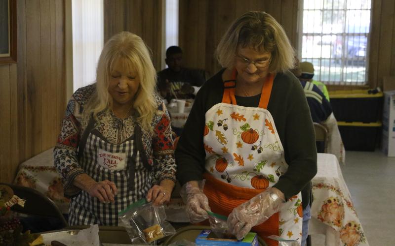 Betty Bussey (left) and Scarlene Dampier bag up pies and cakes to serve with the to-go meals. (MORGAN MCMULLEN/Lake City Reporter)